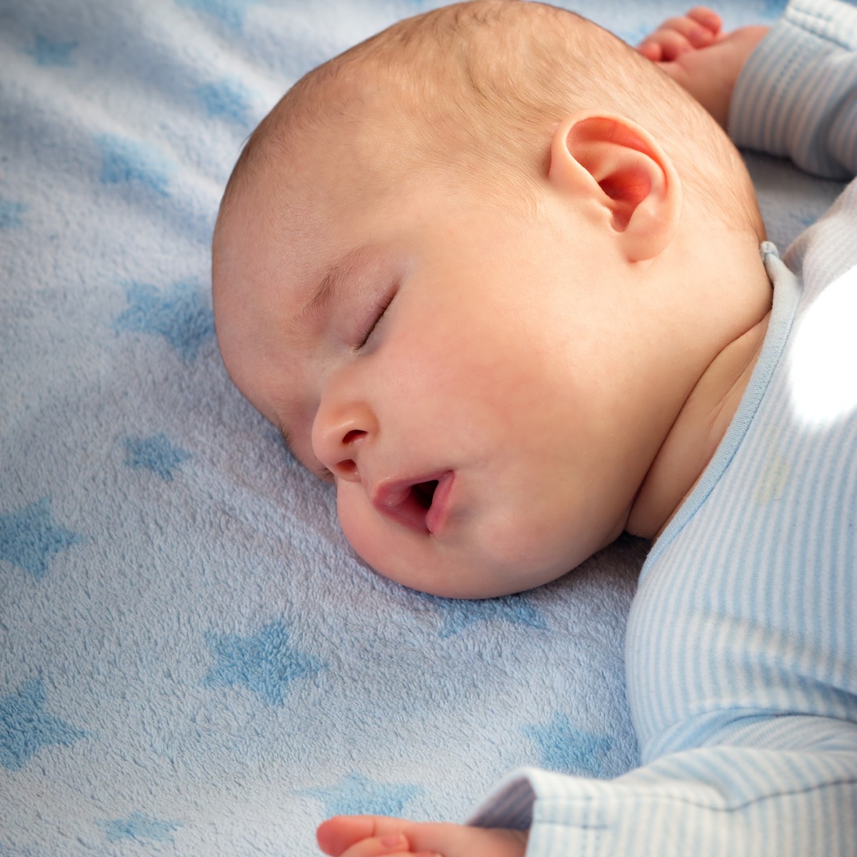 3 month old baby sleeping on blue blanket with stars